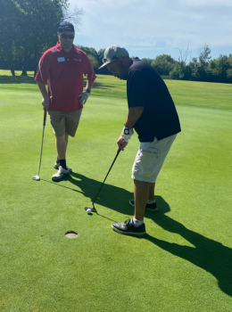 Golfer putts as another golfer watches.